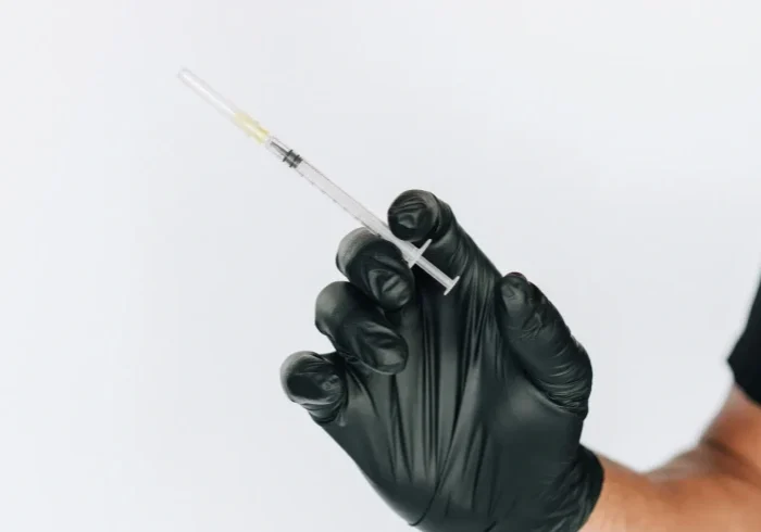 Person with syringe in black gloves