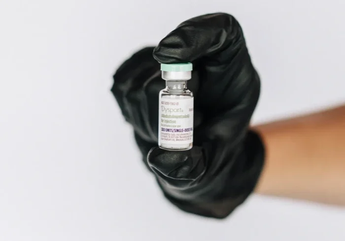 Black glove displaying a medical vial.